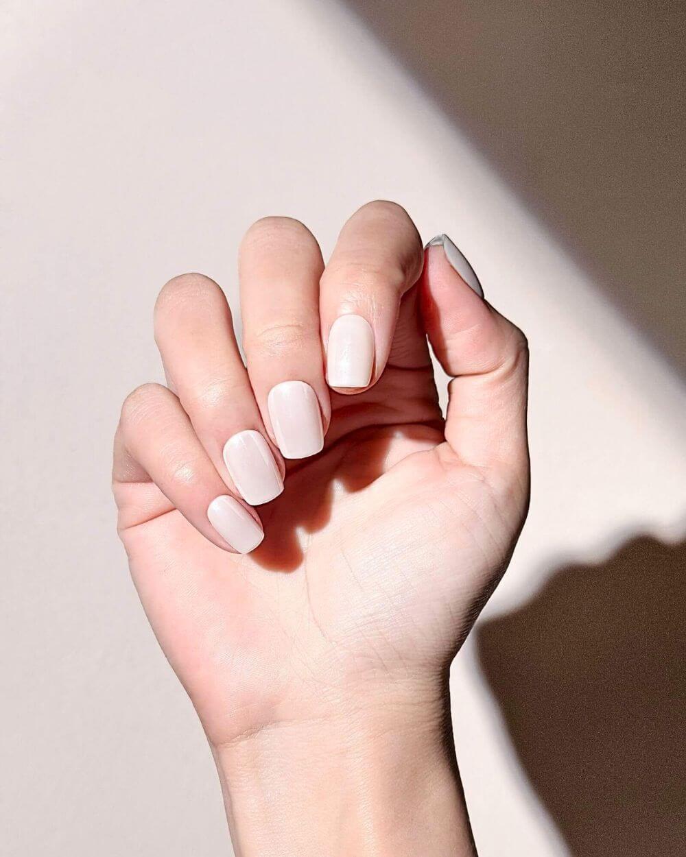 A hand with elegant posture wearing milk white press-on nails from Justmee