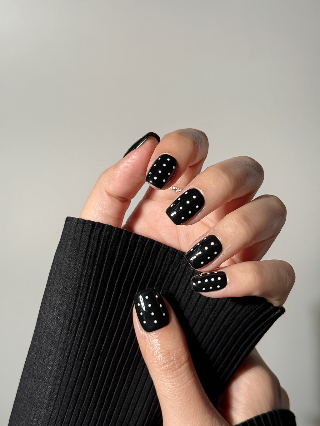 Glossy black short square press-on nails with white polka dot pattern from Justmee, on hand photo
