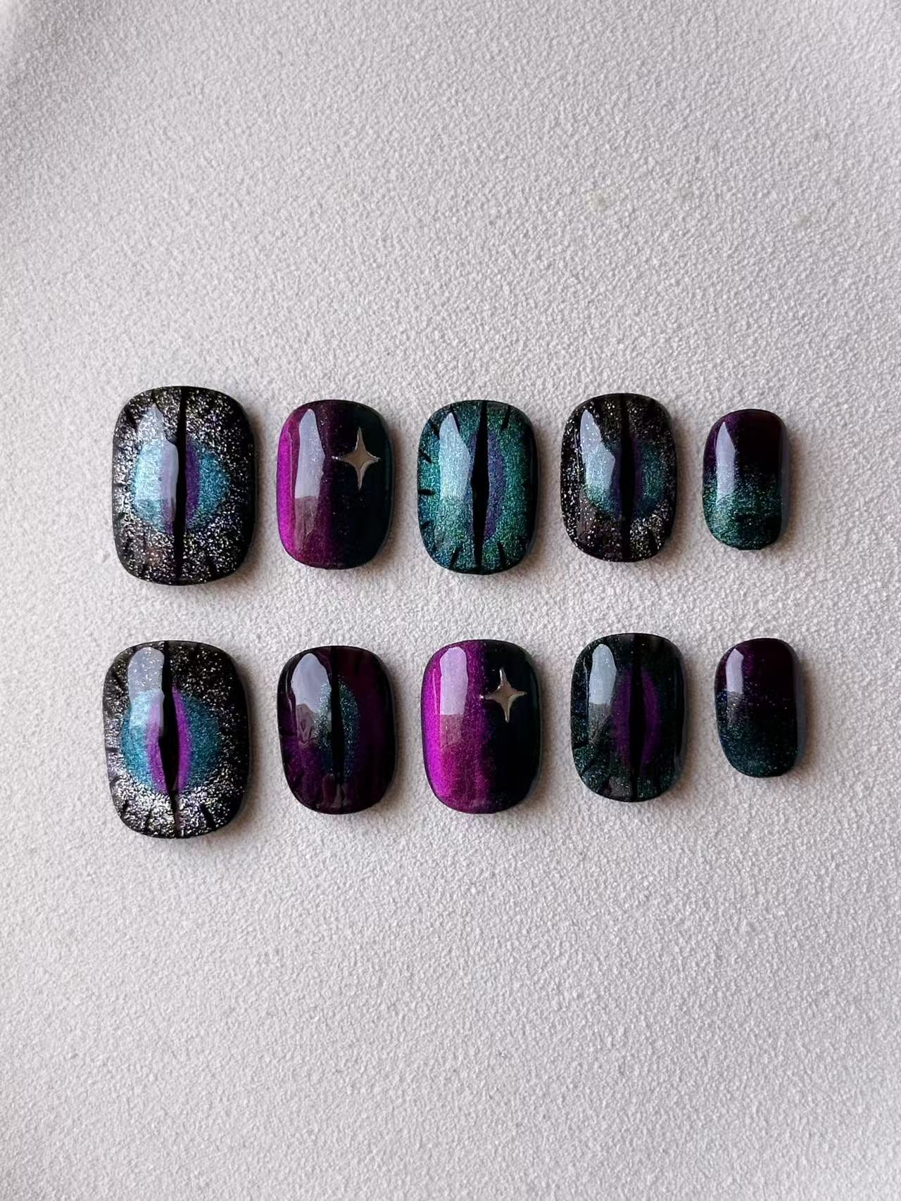 Magnetic cat-eye press-on nails in purple and teal with dragon eye and star designs
