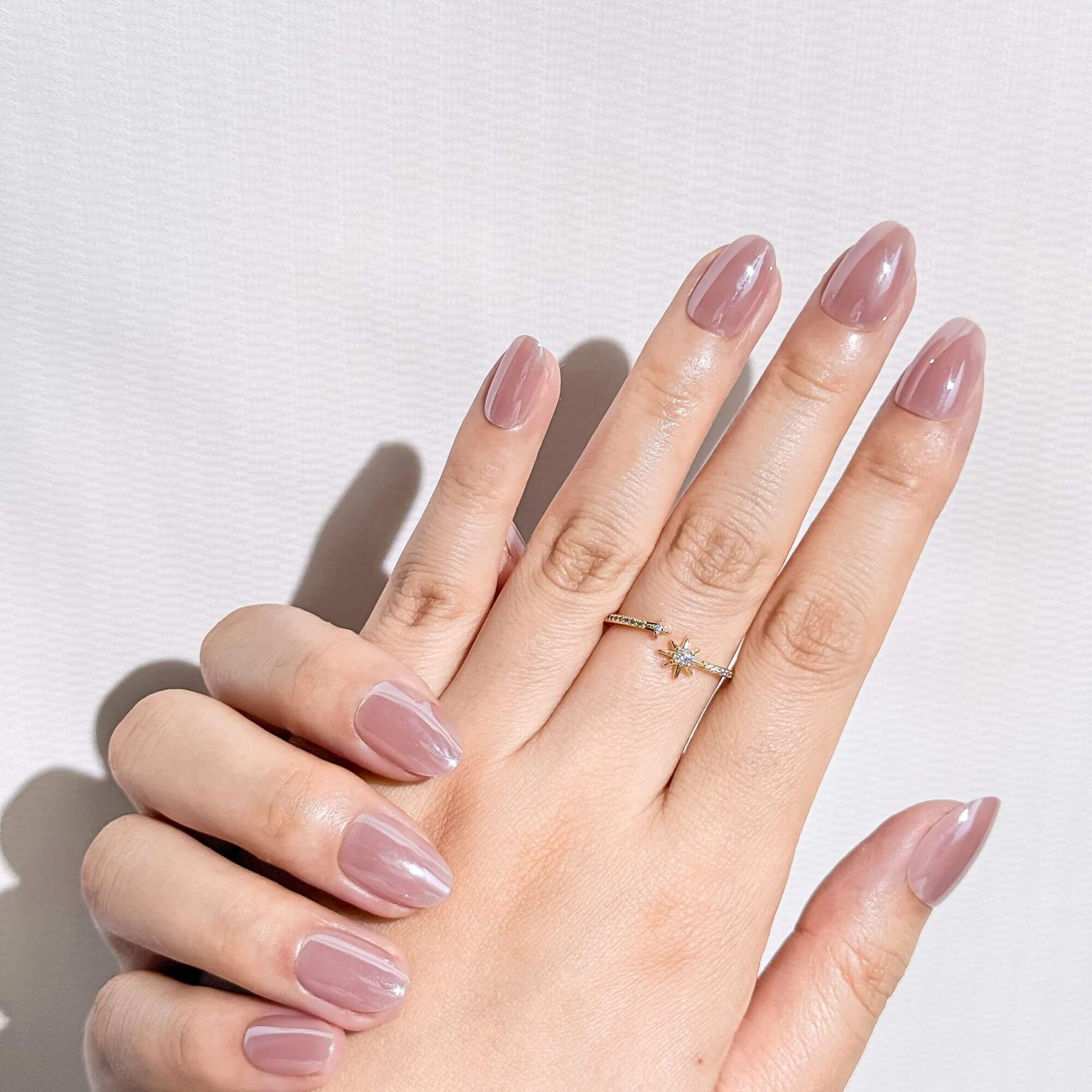 Elegant mauve pink press-on nails in short almond shape, aesthetic artificial nail design for a clean look.