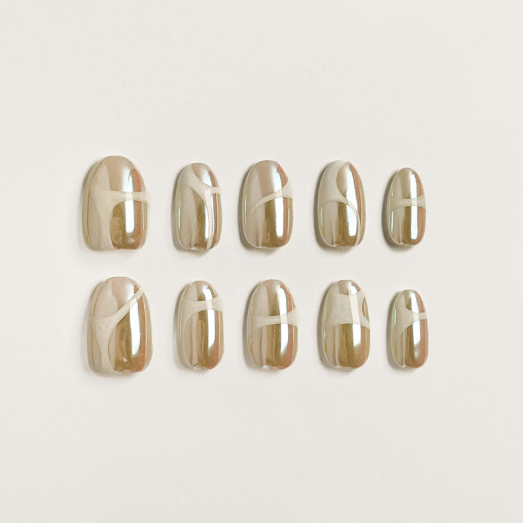 Ein 10er-Set handgefertigte Champagne Glaze Press-on Nails mit weißem abstraktem Wirbel-Design auf Perlmutt-Chrome.