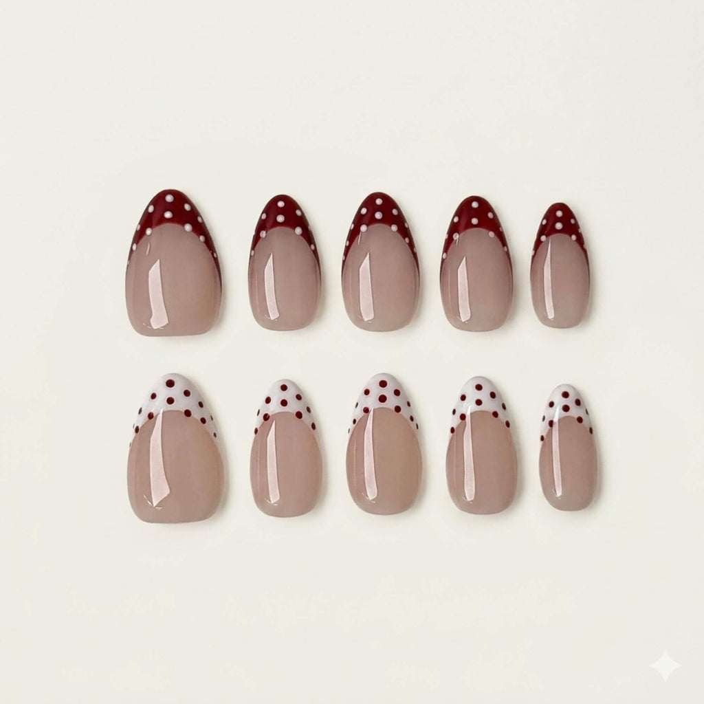 Eine Produktübersicht von 10 handgefertigten mandelförmigen Kunstnägeln mit gemischten rot und weiß gepunkteten French-Tip-Designs aus der Cherry Mix Kollektion.