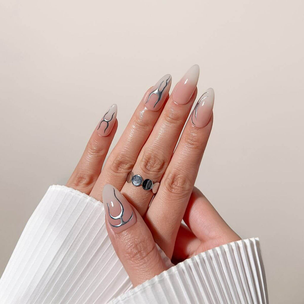 Nahaufnahme der justmee "Chrome Aura" Gel-Nägel zum Aufkleben an der Hand. Kombiniert eleganten Nude-Farbverlauf mit futuristischen silbernen Chrome-Akzenten.
