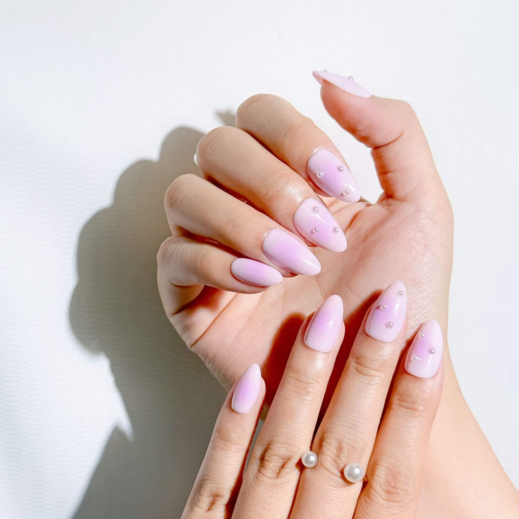 Manicure look with Justmee Lilac Mist pearl-studded stick-on nails, featuring a soft ombré almond shape on hands.