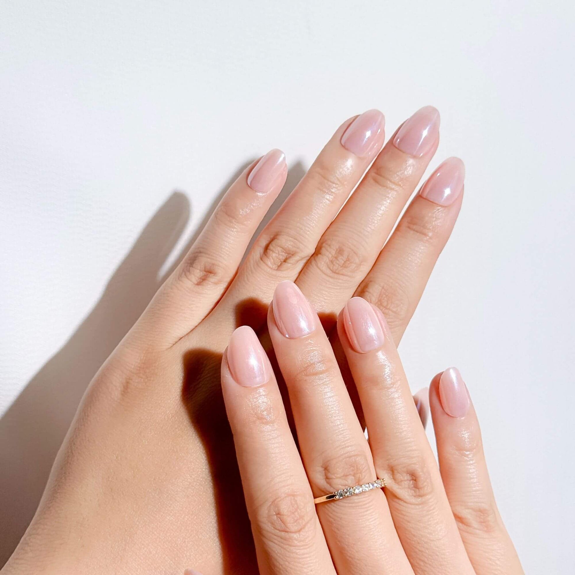 Elegant short almond press-on nails in nude pink pearl finish, perfect for a clean girl aesthetic.