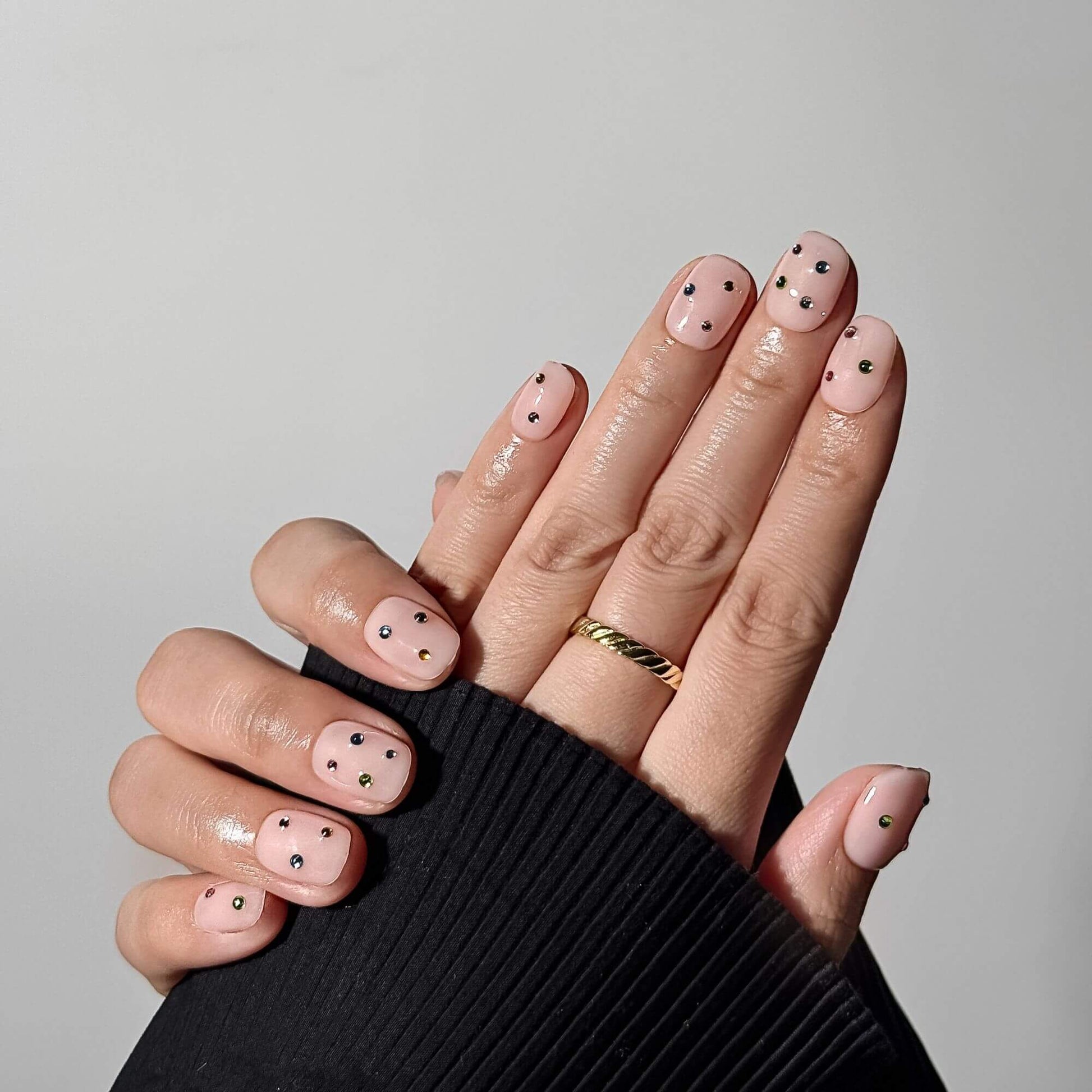 Lifestyle-Foto einer professionellen Maniküre mit den handgefertigten Prism Petal Nägeln zum Aufkleben, das den eleganten Nude-Schimmer und die kurze eckige Form zeigt.