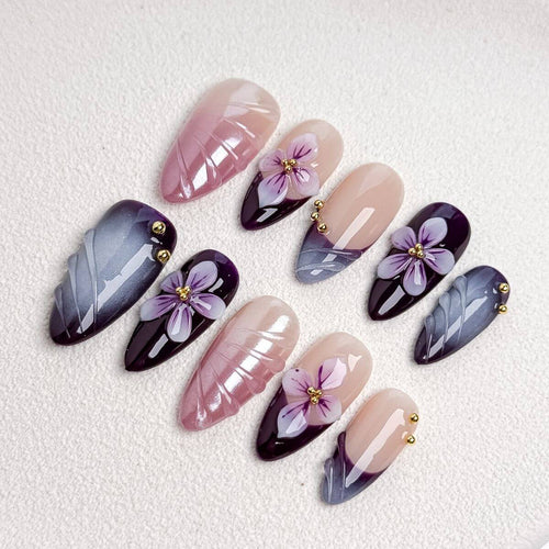 Eine flache Produktübersicht des Amethyst Velvet Sets mit künstlichen Nägeln, die detailliert violette 3D-Blüten, grauen Cat-Eye-Schimmer und altrosa Reliefs zeigt.
