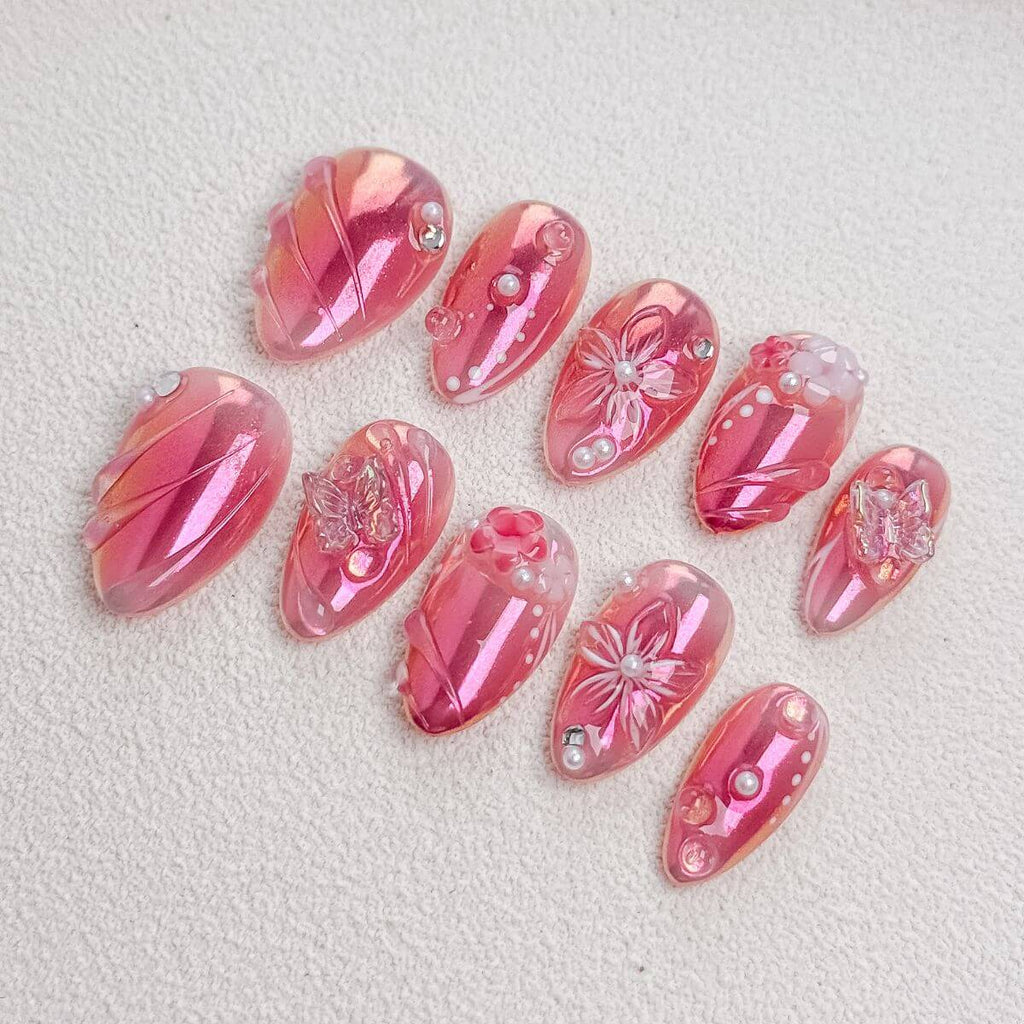 Eine Produktübersicht des Pink Aurora Sets mit künstlichen Nägeln, die pinkfarbenes Chrome-Finish, 3D-Glasschmetterlinge, Blüten-Reliefs und Perlen zeigt.