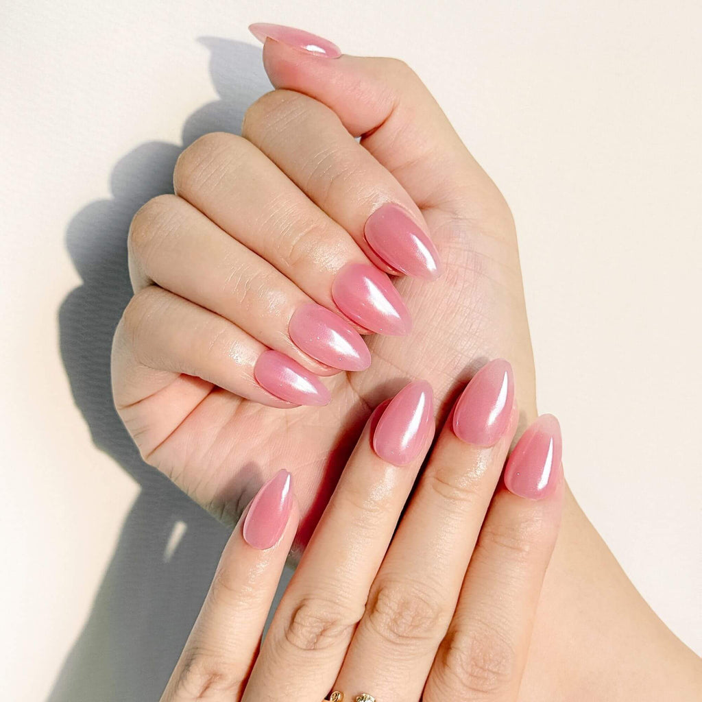 Lifestyle photo of a feminine manicure featuring handmade pink aurora nails that catch the light with a high-gloss, iridescent glaze.
