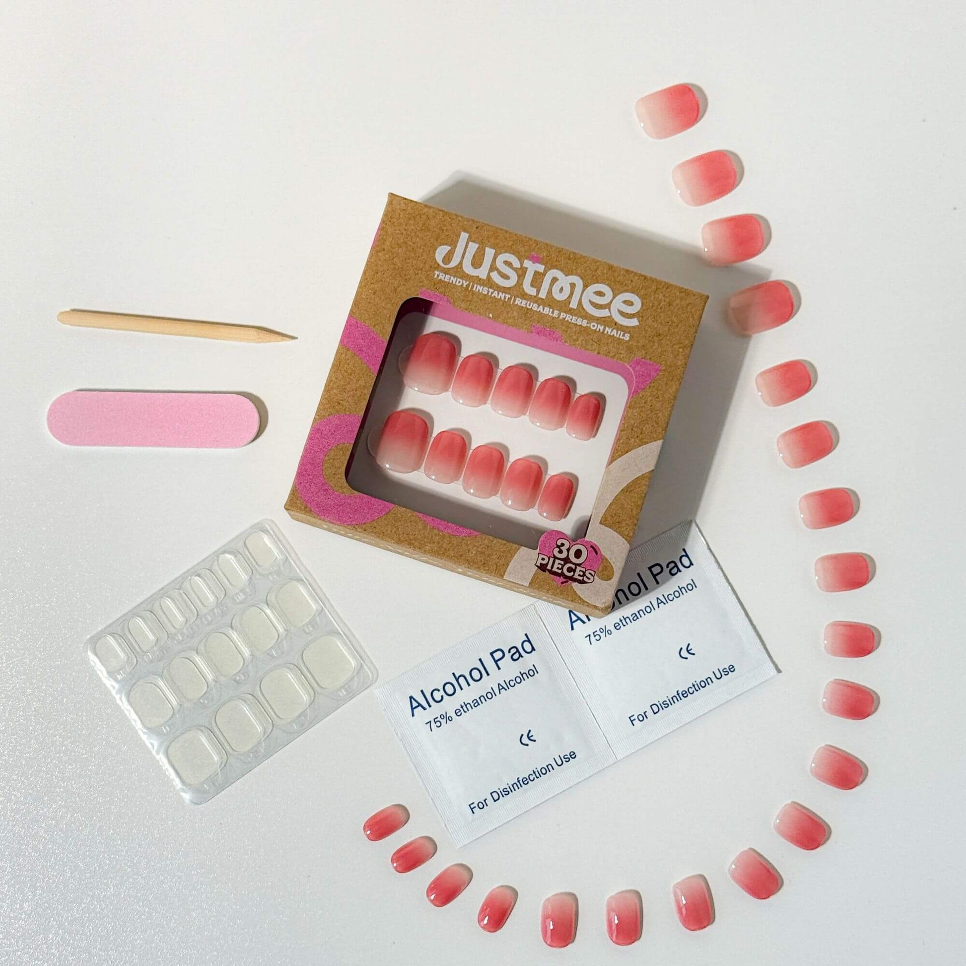 Vollständiges Justmee Press-on-Nagelset bestehend aus 30 Nägeln mit Rosé-Farbverlauf, Klebepads, Reinigungstuch, Rosenholzstäbchen und einer rosa Nagelfeile.