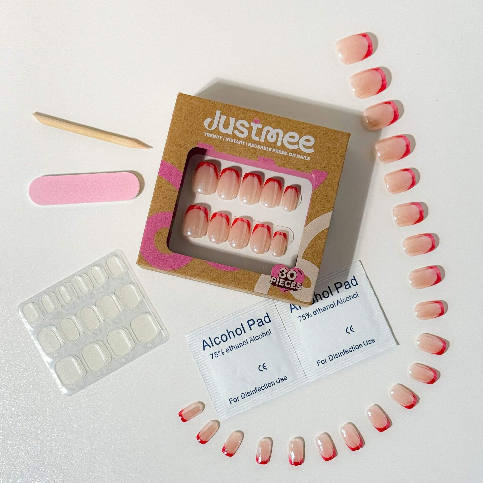 Ein komplettes Justmee Press-on-Nagelset mit 30 kurzen, eckig-abgerundeten Nägeln mit leuchtend roten French Tips, inklusive Klebepads, Nagelfeile und Zubehör.