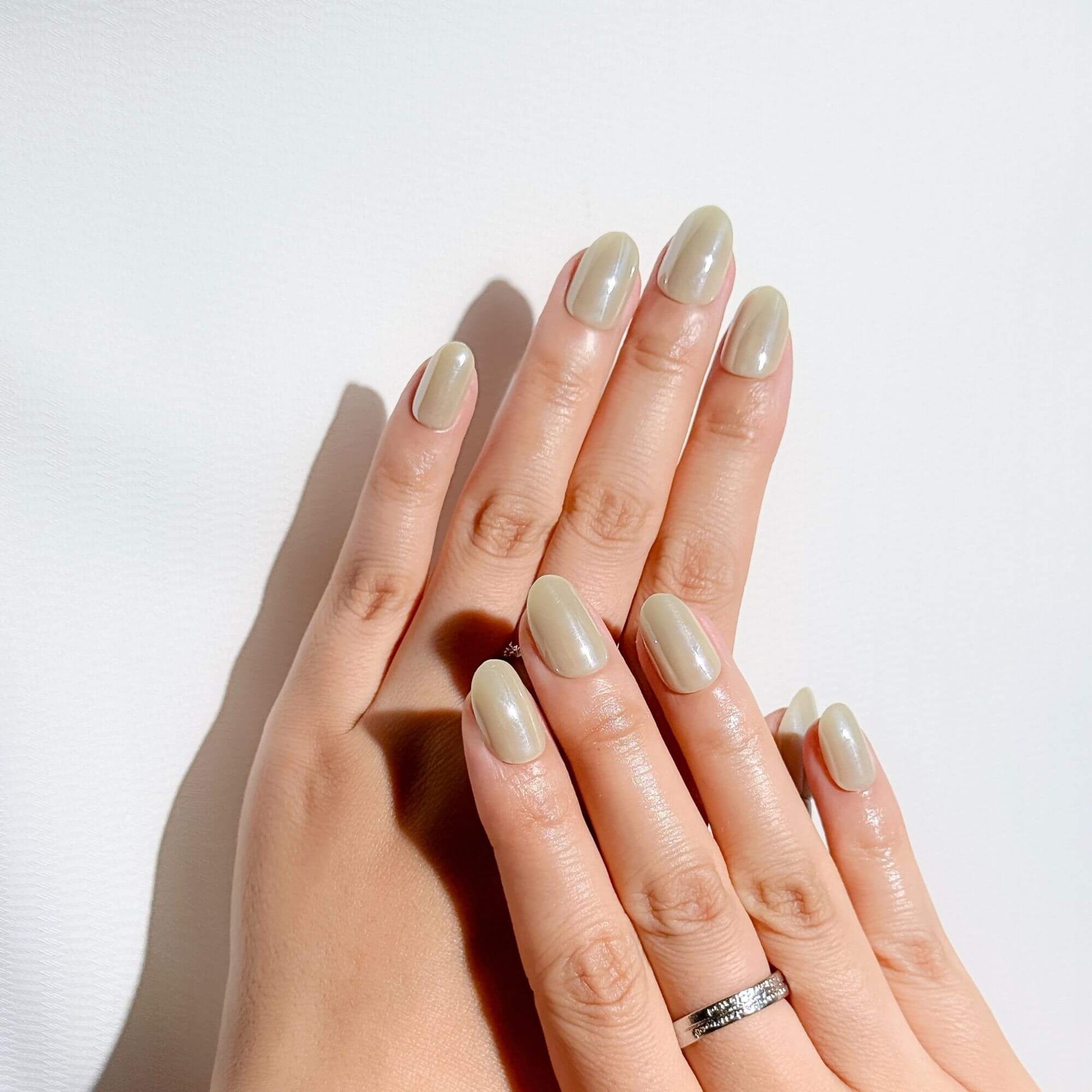 Hände mit Justmee salbeigrünen ovalen Press-on-Nägeln, die einen natürlichen Look in Erdtönen