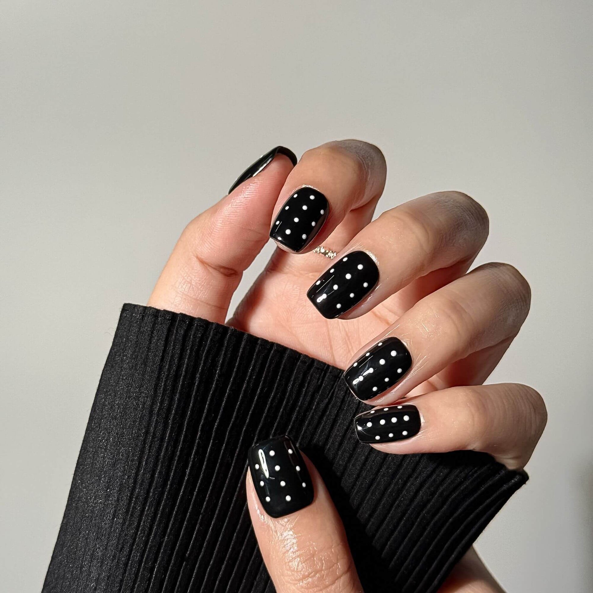 Close-up of handmade short square press-on nails highlighting the crisp white polka dots and the professional glossy finish of the design.