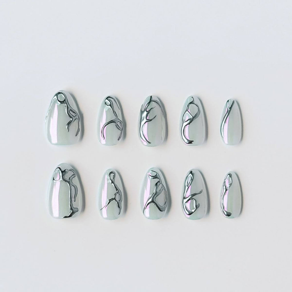 Ein 10er-Set handgefertigter Press-on Nails in Mandelform mit milchig-schimmernder Basis und silbernem 3D-Chrom-Design im futuristischen Y2K-Stil.
