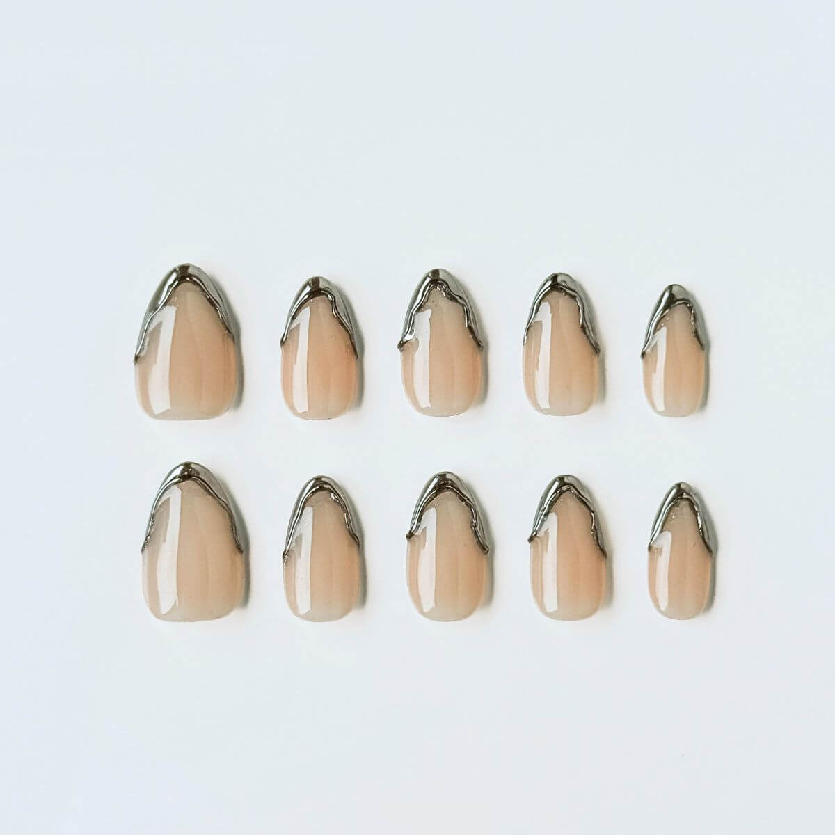 Flatlay von The Chrome French Kunstnägeln. Nude Gel-Basis mit 3D Chrome-Drip-Spitzen für eine moderne Interpretation der French Nails.