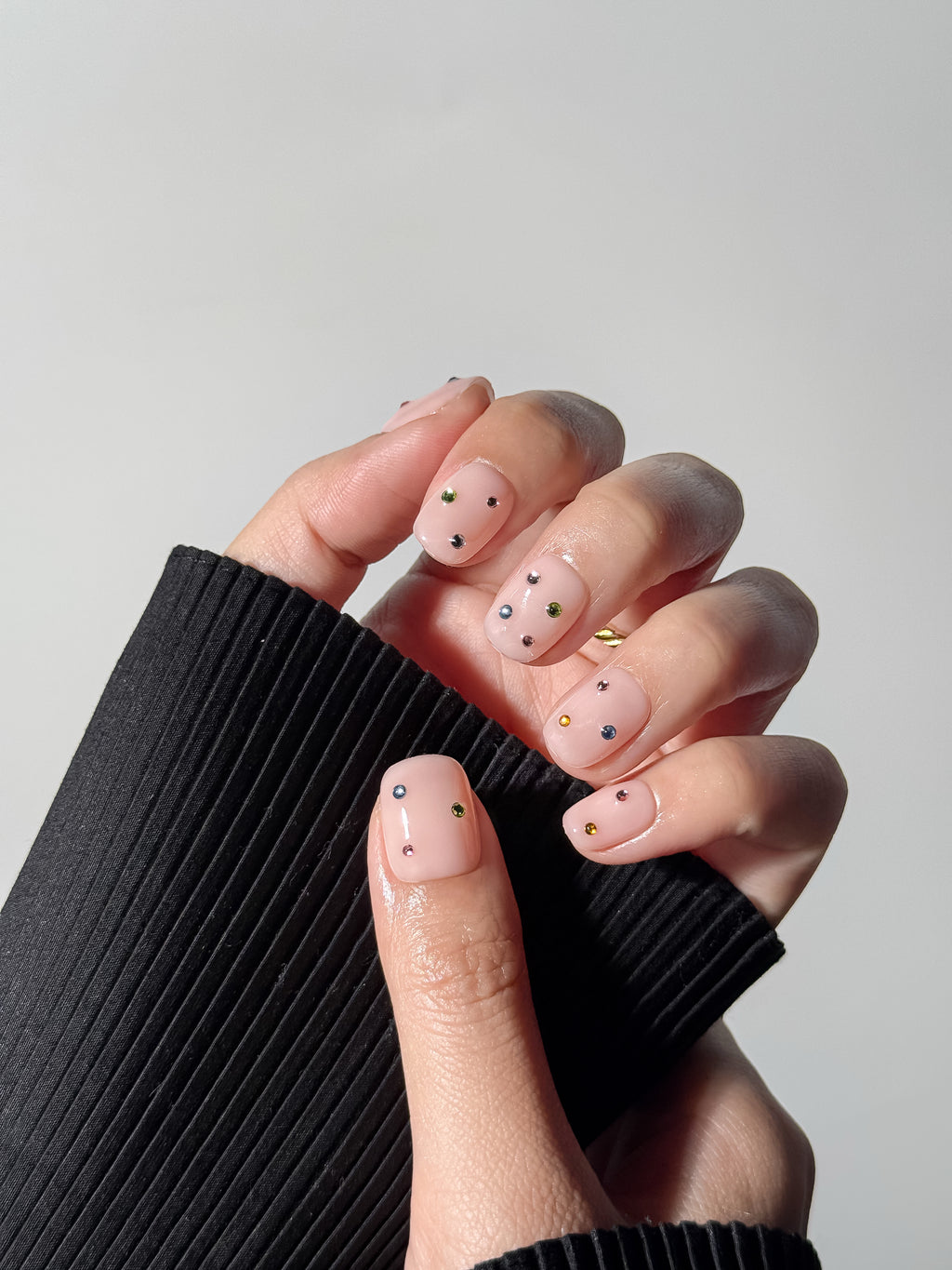 Model wearing Twinkle Pop nude press-on nails with multicolored crystals – reusable and easy to put on in 10 minutes